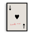 Minimalist art print of the Ace of Hearts playing card with large black heart symbol and handwritten red text “Lucky me” across the card on a light background.