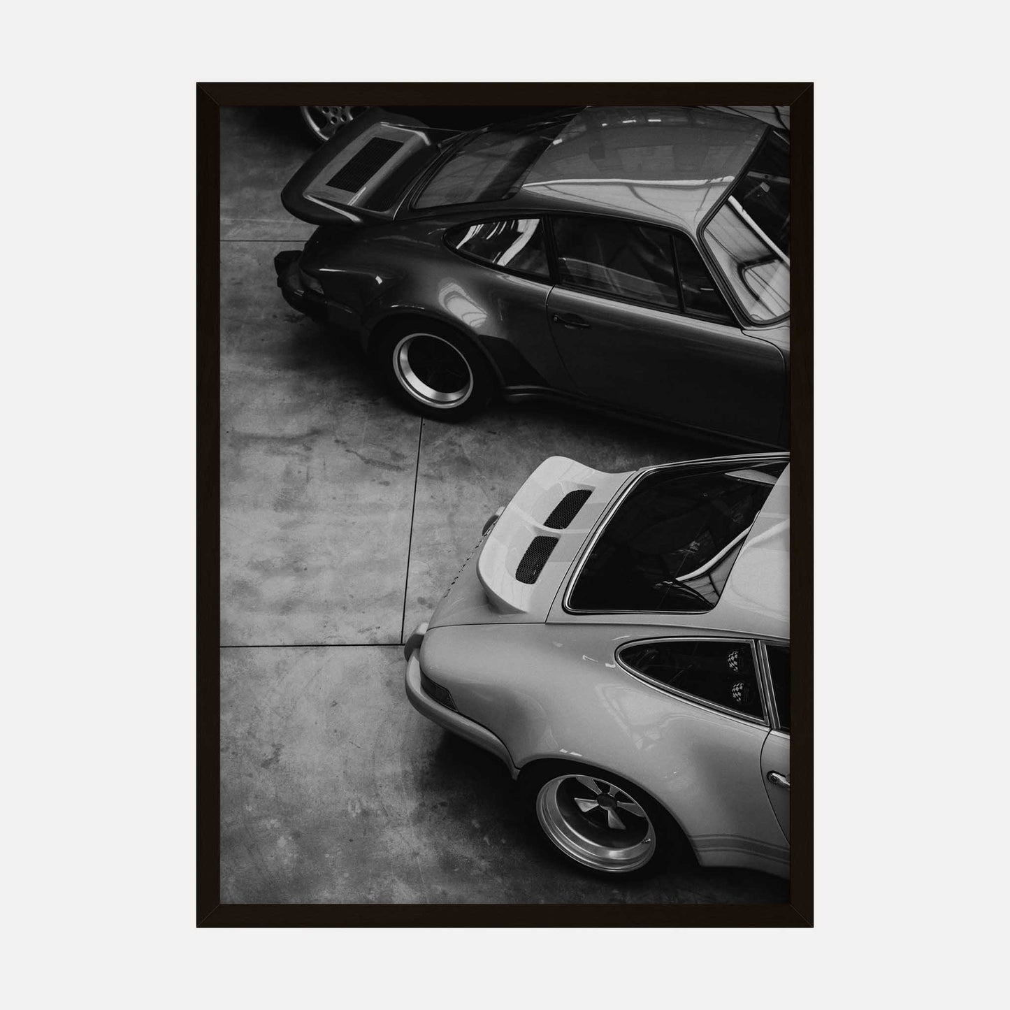 Black and white art print featuring an overhead view of vintage cars parked on a concrete floor.