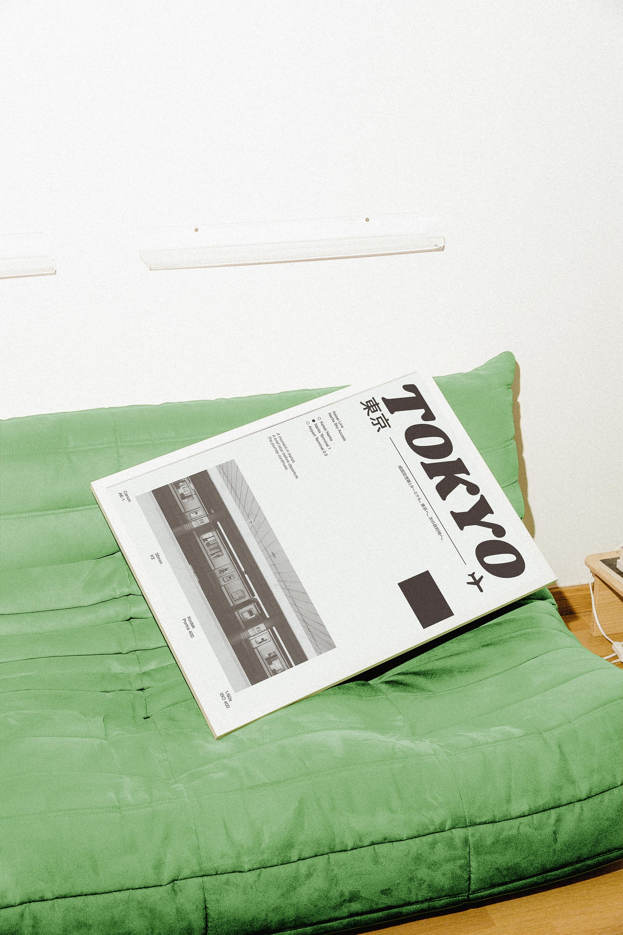 Framed Tokyo art print in black and white, displayed on a green futon against a minimal white wall.