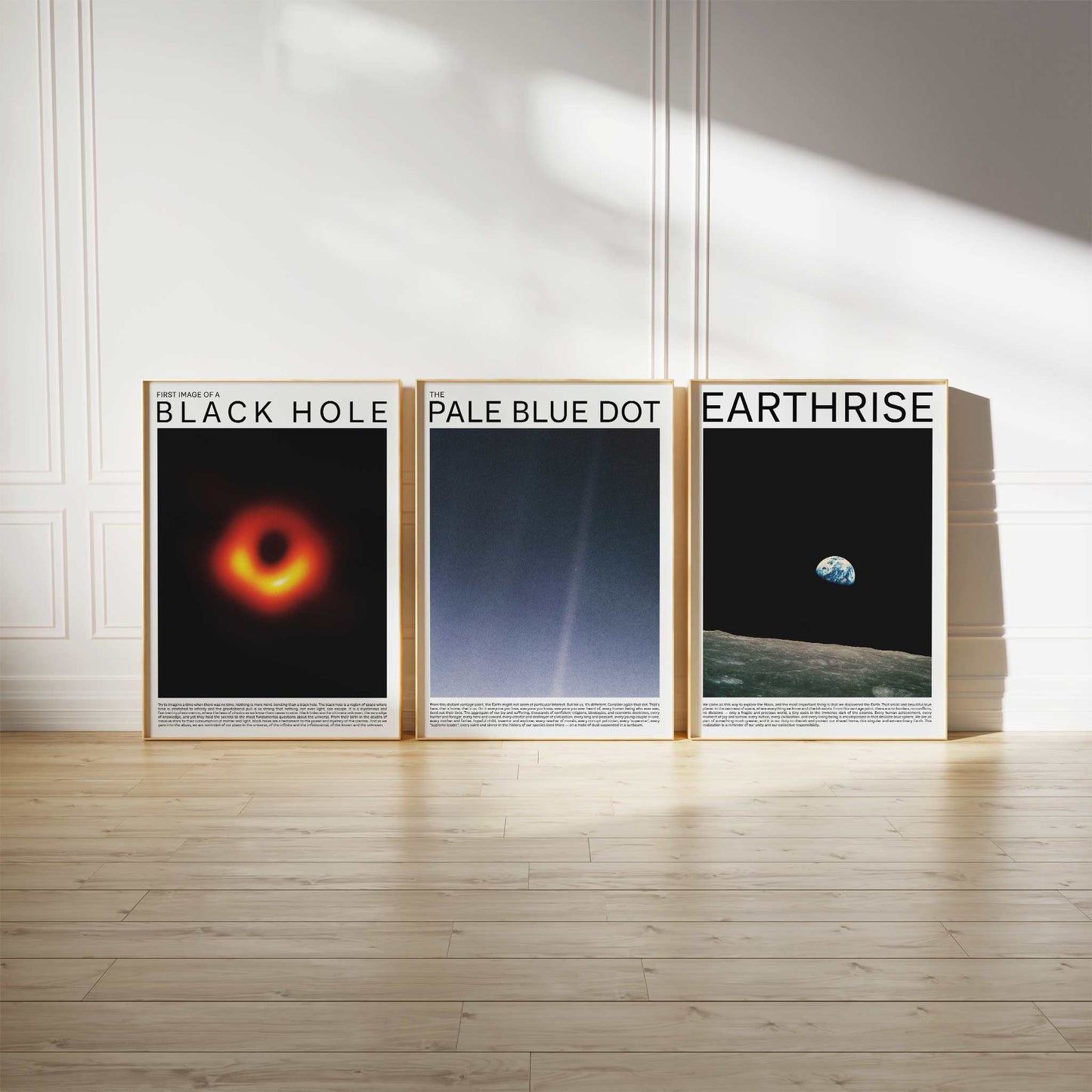 Space Photography Art Print Set featuring iconic images of Black Hole, Pale Blue Dot, and Earthrise, displayed in wooden frames on a light-colored floor against a white wall.